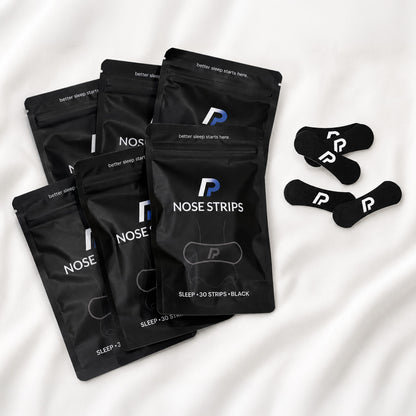 Six nose strips pack bundle with black nasal strips on white bedding