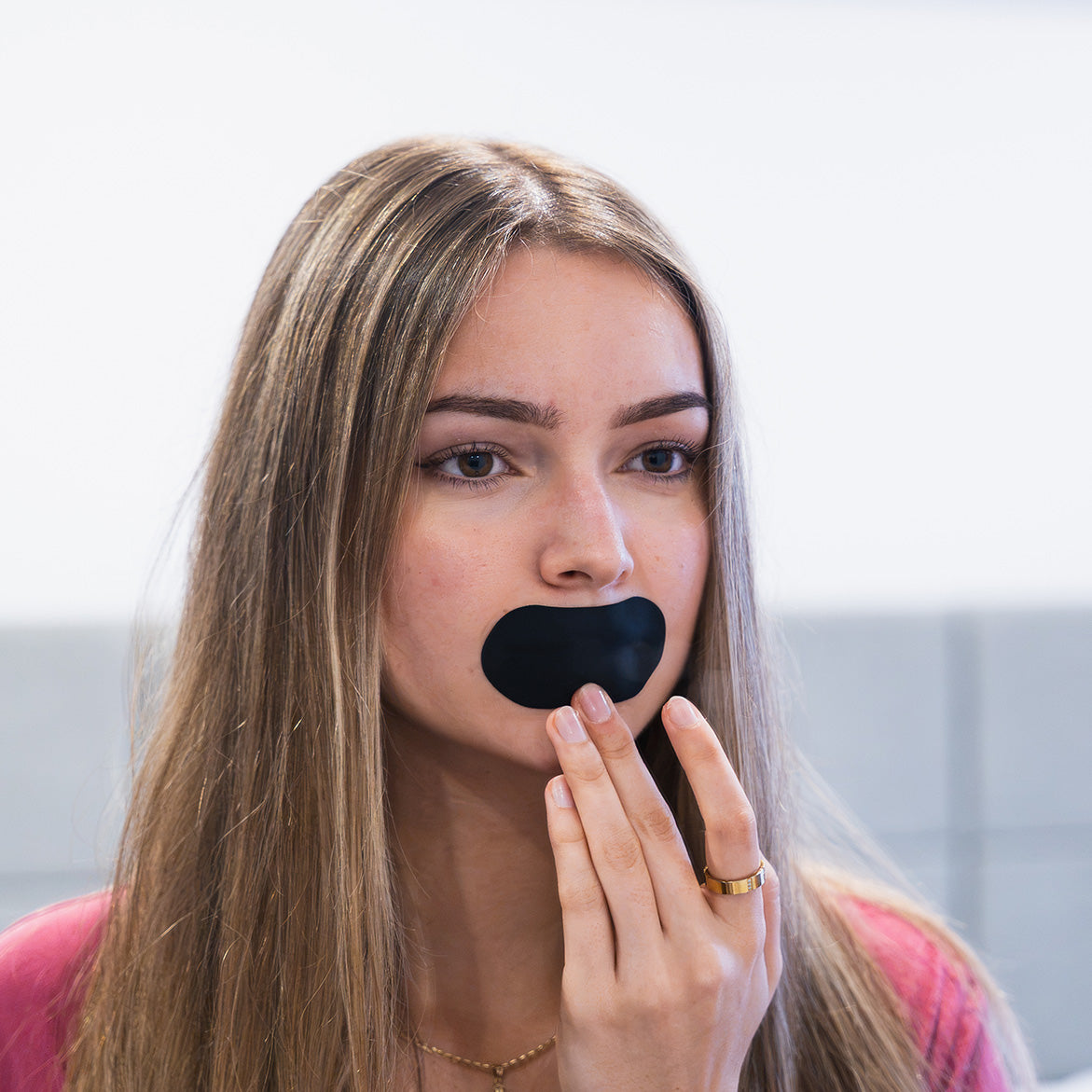 Woman applying black mouth tape in a bright room