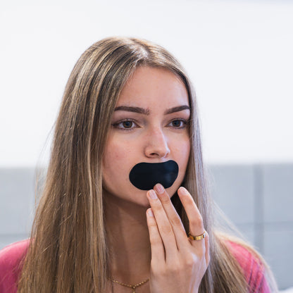 Woman applying black mouth tape in a bright room