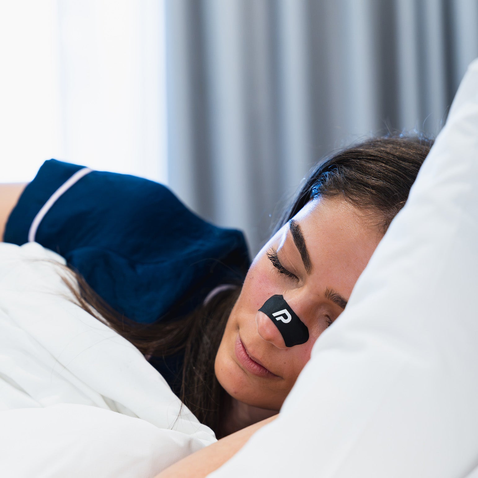 Woman sleeping on her side wearing a black nasal strip