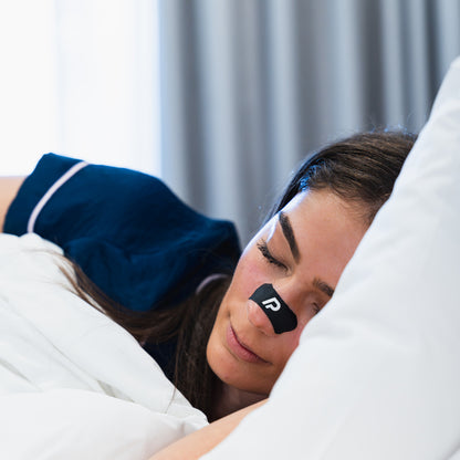 Woman sleeping on her side wearing a black nasal strip